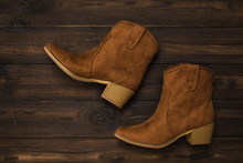 Fashionable Suede Brown Boots With Heels On A Dark Wooden Background. Flat Lay.