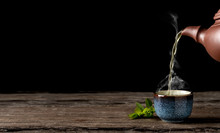 Hot Green Tea Is Poured From The Teapot Into The Blue Bowl, Vintage Wooden Table, Steam Rises Above The Cup. Tea Leaves Next To The Cup. Close-up, Tea Ceremony, Minimalism, Copy Space For Text.