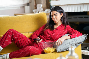 Wall Mural - Persian woman at home watching TV and using remote control