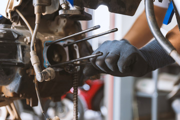 motor style. mechanic fixing motorcycle with soft-focus and over light in the background