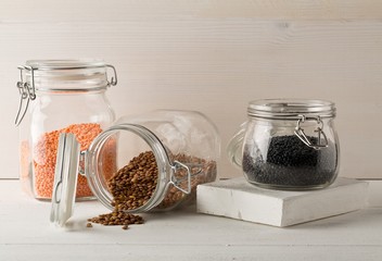 Wall Mural - Different assorted lentils mix with red, brown and black beluga lentils in glass storage jars on white wooden table background