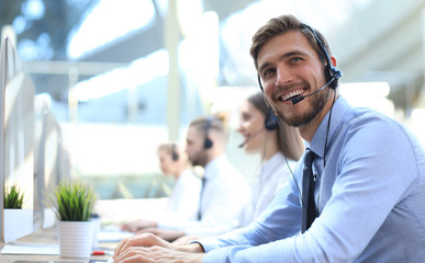 Wall Mural - Portrait of call center worker accompanied by his team. Smiling customer support operator at work.