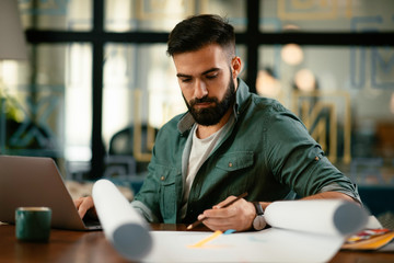 Young businessman working with laptop at office. Businessman sitting at office desk working on laptop computer.