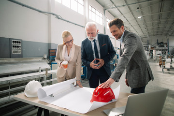 Colleagues working on project. Team of architects discussing business in factory.	