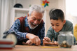 © JustLife - Grandpa and grandson saving money. Grandfather teaching grandchild how to save money.