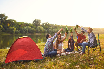 Wall Mural - Young people drink, eat and clink glasses at a picnic