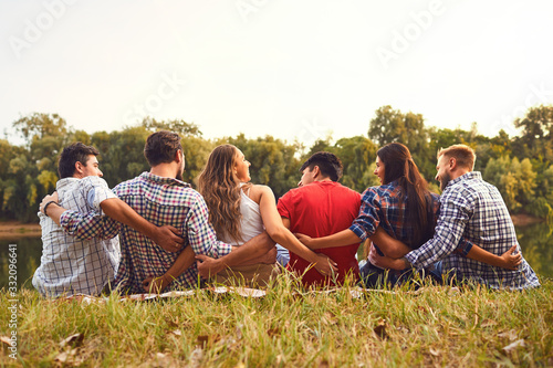 Fotomural Young people sit on the grass hugging in nature in the park