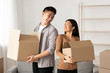 © Prostock-studio - Happy asian family holding cardboard boxes in new flat