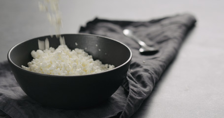 Wall Mural - cottage cheese falling into black bowl closeup