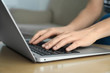 © New Africa - Woman working on modern laptop at wooden table indoors, closeup