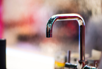 The stainless steel tap that is not closed is having a drop of water.