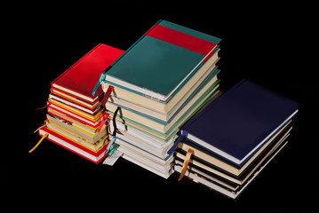 Many hardcover books on black background. Stack of books with white and yellow pages.