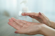 Female hands using wash hand sanitizer gel pump dispenser. Clear sanitizer in pump bottle, for killing germs, bacteria and virus.