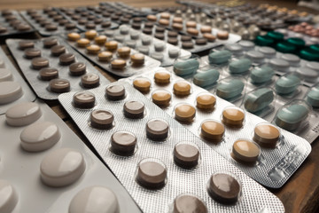 Closeup shot of different pills on table with tablets , pharmaceutical industry concept