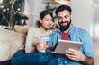 © Mediteraneo - Smiling couple using digital tablet and credit card at home