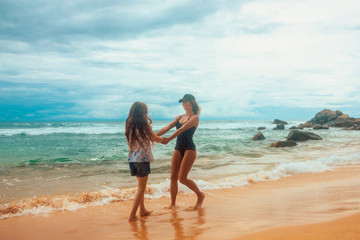 Wall Mural - family relationship, mother with daughter are walking on the beach and smiling together. vacation concept, free space	