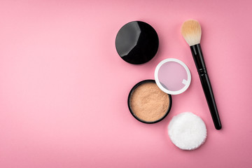 Makeup brush and powder on pink background.