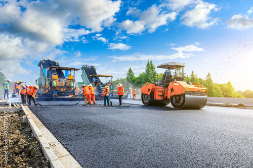 Fotomural Construction site is laying new asphalt road pavement,road construction workers and road construction machinery scene
