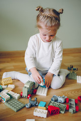 Wall Mural - Little girl play a building plastic blocks. Logic game for children.