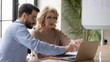 © fizkes - Concentrated diverse colleagues sit at desk in office brainstorm discuss business ideas using laptop, focused businesspeople cooperate consider project working on computer at meeting together