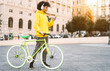 © Alessandro Biascioli - Happy Afro man using mobile smartphone outdoor - Young guy having fun listening music with headphones while riding with bike in city - Youth millennial generation lifestyle and technology concept