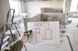 © malkovkosta - The construction worker hold in hands Architectural blueprints. Repair or construction of a new apartment. Concept for new house design or home improvement. Development of the apartment project.