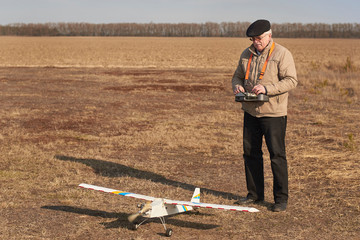 Wall Mural - A man controls a radio-controlled aircraft on the field in early spring.