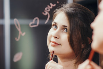 reflection of young woman in mirror with inscription 