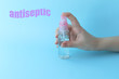 © Tatyana - A small pink bottle with antiseptic in hand on a blue background. Selective focus. Label with the text 'Antiseptic'. Prevention of coronavirus