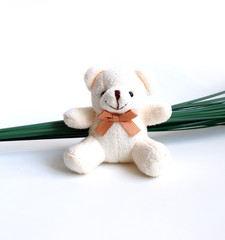 Soft toy bear, white, sitting on a branch of flowers.