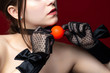 © Grispb - BDSM entertainment. A girl in black lace gloves is holding a BDSM gag. Orange BDSM gag. Sexual game. Sexual dominance.