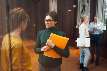 Group of positive female office employees have meeting at workplace at modern office. Business people discussing together working process