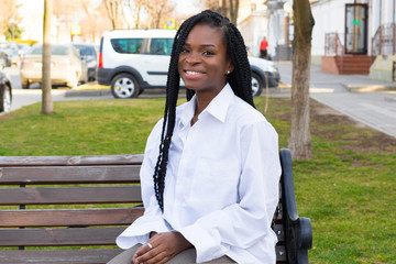 Wall Mural - Close up portrait of a beautiful young african american woman with pigtails hairstyle in a business suit and white oversized blouse walks the street