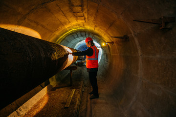Wall Mural - Tunnel worker examines pipeline in underground tunnel