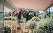 canvas print picture - Handwerker stellt die Markise mit einem Inbus Schlüssel ein auf der Terrasse im Garten