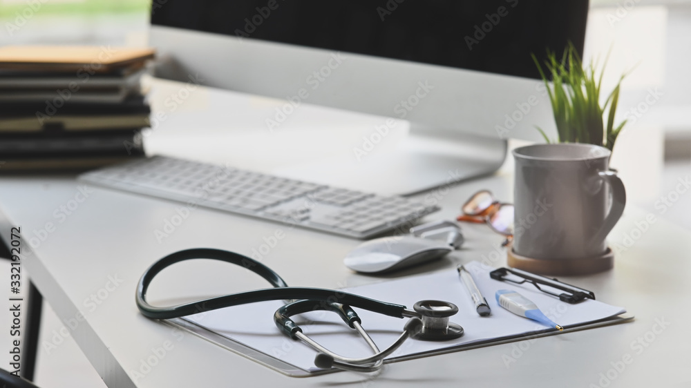 Stethoscope putting on white working desk with Coffee cup, Potted plant, Clipboard, Wireless mouse and keyboard, Stack of books, Doctor workspace in medical centre. - obrazy, fototapety, plakaty 