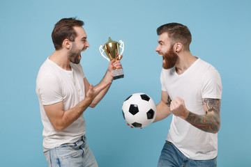 Screaming two men guys friends in white t-shirt isolated on pastel blue background. Sport leisure lifestyle concept. Cheer up support favorite team with soccer ball, football cup doing winner gesture.