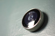 Nest smart home thermostat on blue wall from below. Green technology saves money heating and cooling in home