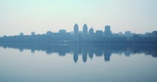Silhouette Of A Big City Over The Water. Birds. Calm. Morning.