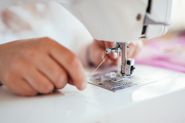 Seamstress puts a thread on a needle in a sewing machine