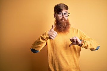 Sticker - Handsome Irish redhead man with beard wearing glasses over yellow isolated background Doing thumbs up and down, disagreement and agreement expression. Crazy conflict