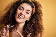 Young beautiful woman with curly hair and piercing holding dental aligner orthodontic very happy pointing with hand and finger