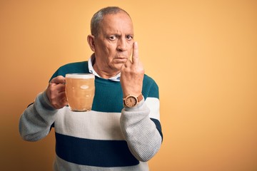 Sticker - Senior handsome man drinking jar of beer standing over isolated yellow background Showing middle finger, impolite and rude fuck off expression