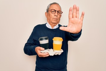 Poster - Senior handsome hoary man holding tray with takeaway cups of coffee over white background with open hand doing stop sign with serious and confident expression, defense gesture