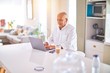 © Krakenimages.com - Senior handsome man smiling happy and confident. Sitting using laptop and drinking cup of coffee at home