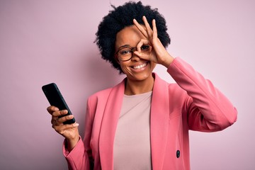 Young African American afro woman with curly hair having conversation using smartphone with happy face smiling doing ok sign with hand on eye looking through fingers