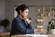 © fizkes - Thoughtful Indian woman looking at laptop screen, pondering task, businesswoman freelancer working on difficult project, pensive female student preparing to exam or test, doing homework