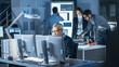 © Gorodenkoff - Shot of Industrial Engineer Working in Research Laboratory / Development Center, Using Computer. In the Background Technology Development Laboratory with Scientists, Engineers Working