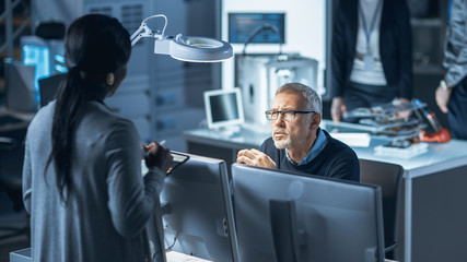 Fototapete - Shot of Male Industrial Engineer Talking with Female Manager about New Efficient Engine Concept Design. Diverse International Team of Industrial Engineers and Scientists Working in Development Center.