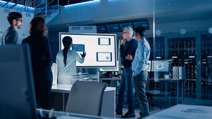 Fototapete - Engineers Meeting in Technology Research Laboratory: Male Engineer Leads Presentation Using Digital Whiteboard, Shows Machine Blueprint, Data Analytics and Neural Network while Colleagues Listening